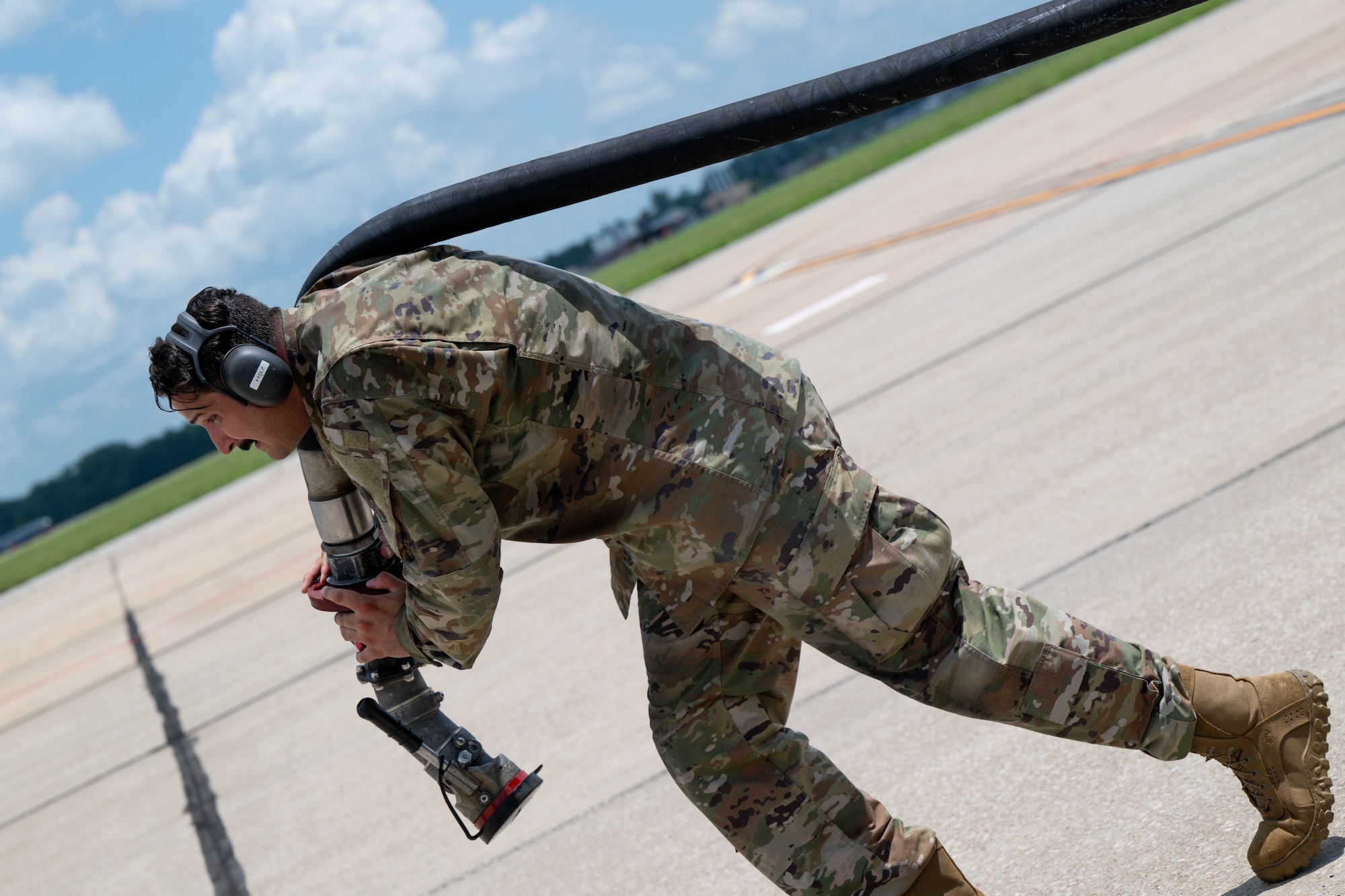 a man pulls a fuel hose from over his right shoulder