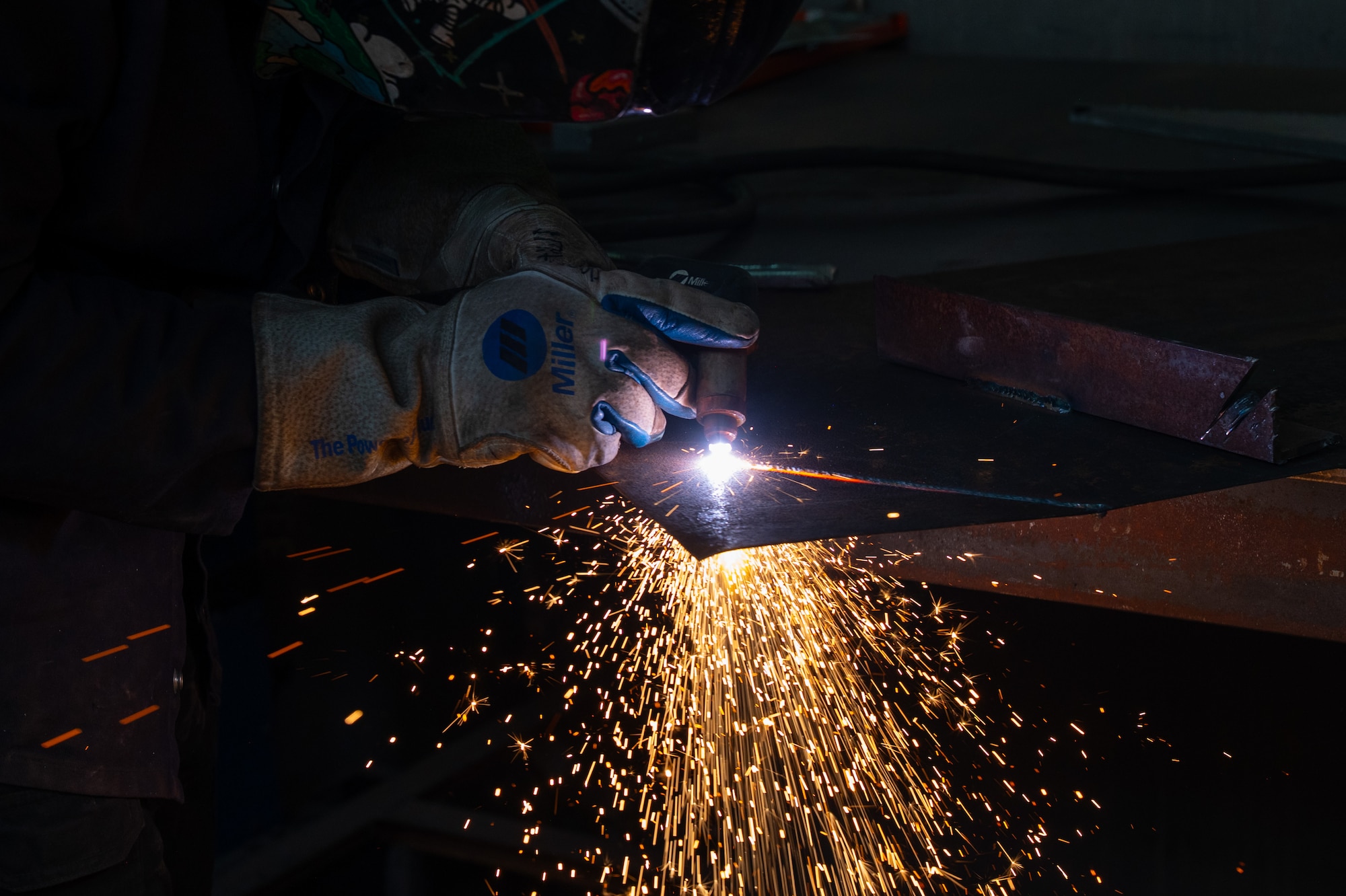 Airman uses a plasma cutter to cut a metal component