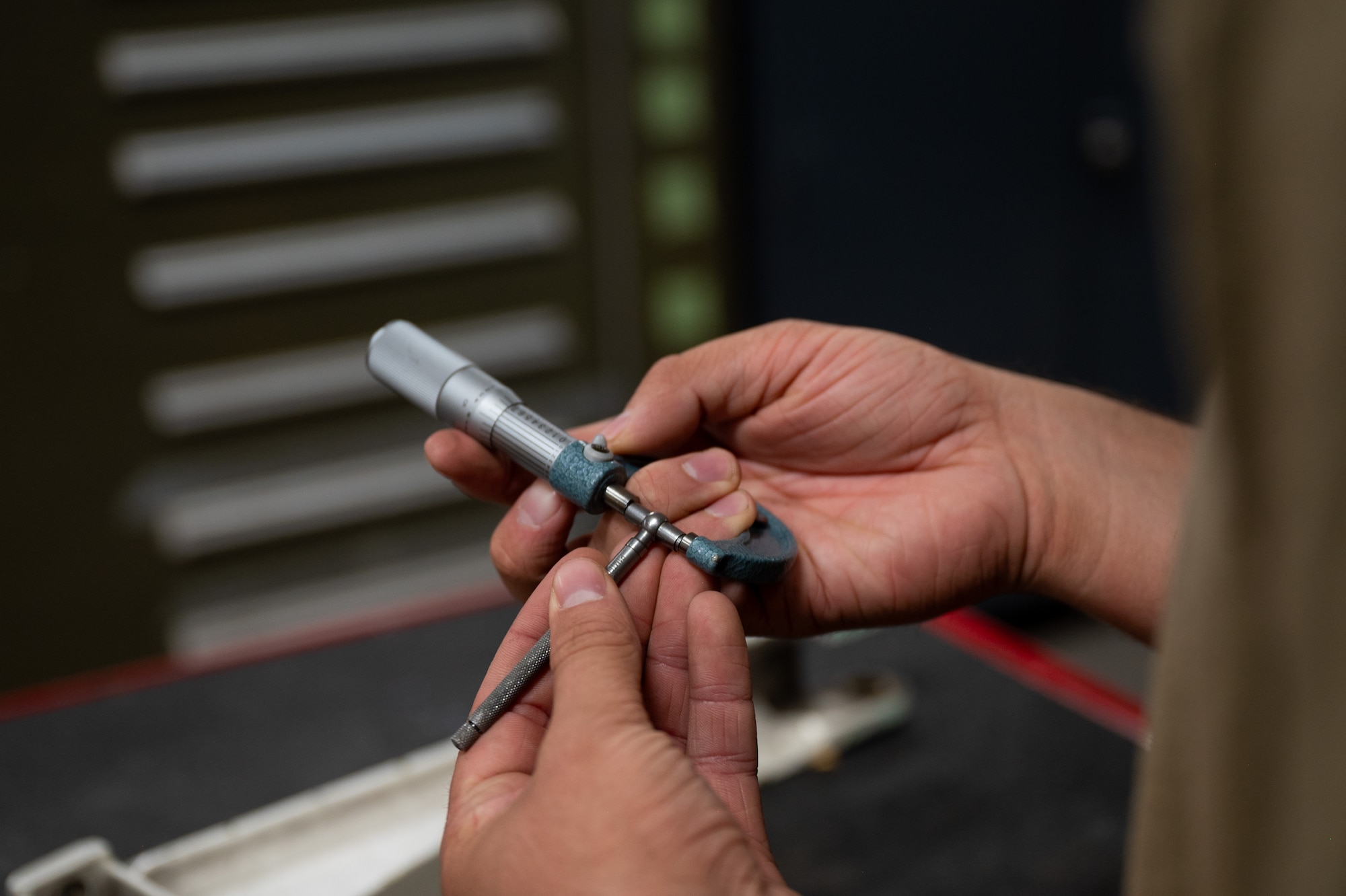 Airman uses a micrometer to measure the length of an aircraft part