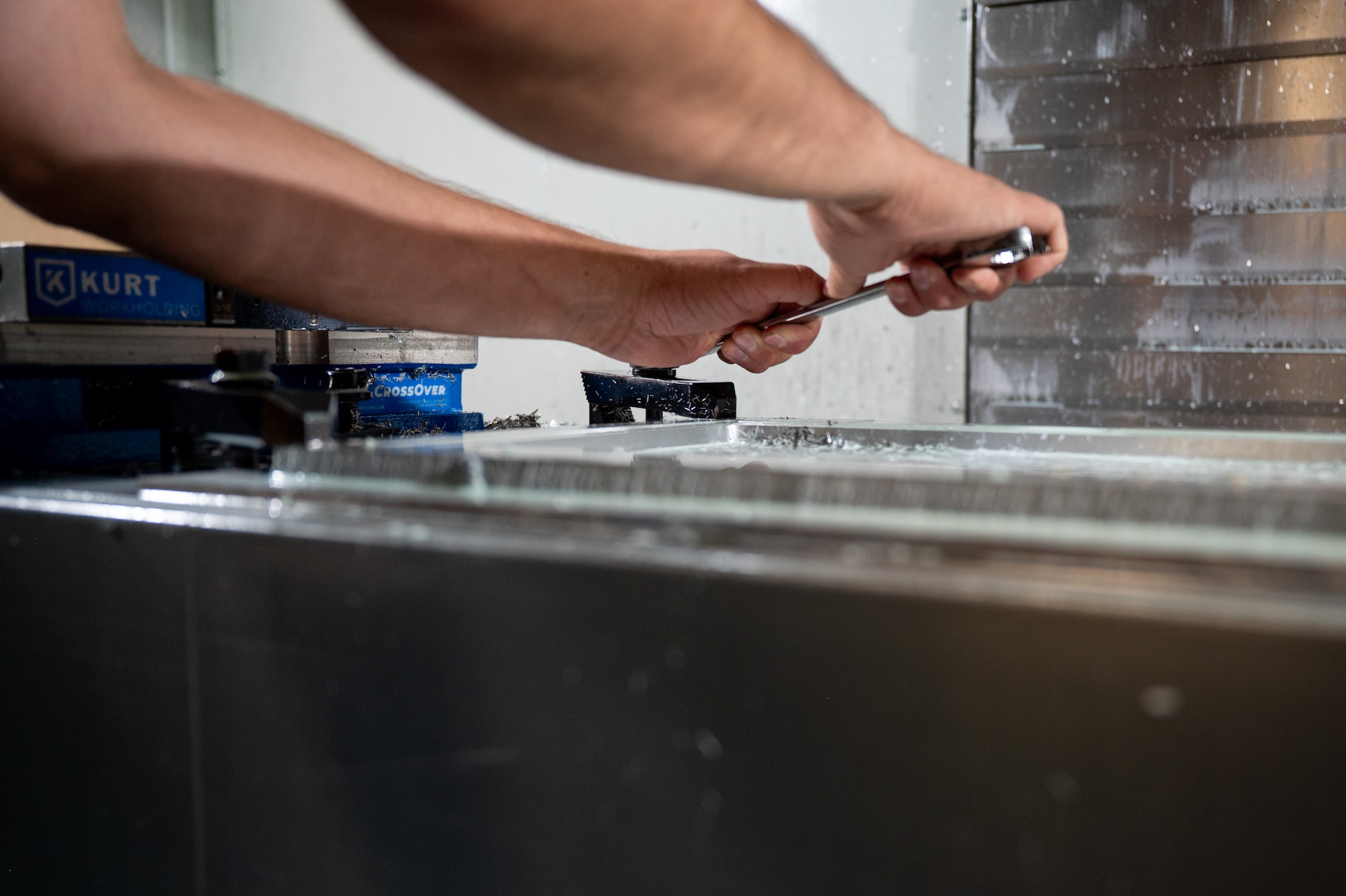 Airman turns a wrench in a CNC machine