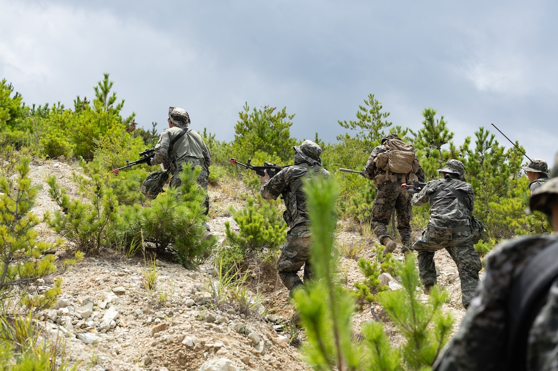 A U.S. Marine with 2nd Battalion, 23rd Marines, forward deployed with 4th Marine Regiment, 3d Marine Division as part of the Unit Deployment Program, and Republic of Korea Marines assault through a simulated enemy position during the Korean Marine Exercise Program 25.2 in Pohang, South Korea, August 5, 2025. KMEP is conducted regularly between the ROK and U.S. Marine Corps to increase their combined capabilities through realistic training geared towards deterrence and maintaining peace in the Indo-Pacific. (U.S. Marine Corps photo by Lance Cpl. Van Hoang)