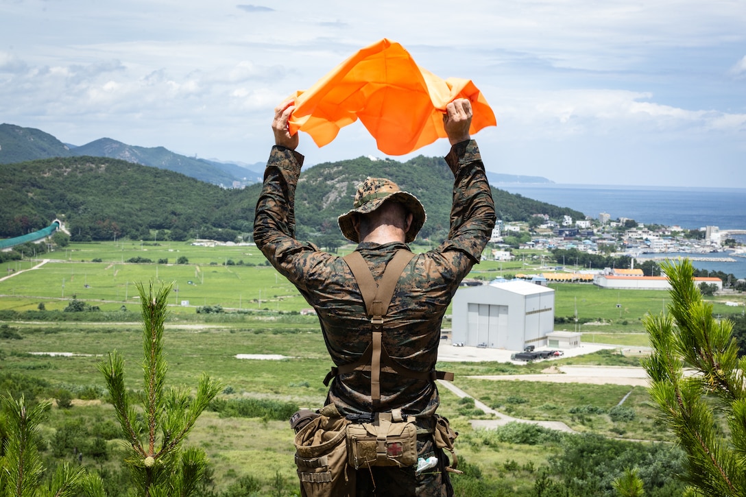 U.S. Marine Corps Cpl. Cole Morrison, a Multi-role, Anti-armor Anti-personnel Weapon System gunner with 2nd Battalion, 23rd Marines, forward deployed with 4th Marine Regiment, 3d Marine Division as part of the Unit Deployment Program, waves a signal panel marker to friendly forces after securing a simulated enemy position following an amphibious assault during the Korean Marine Exercise Program 25.2 in Pohang, South Korea, August 5, 2025. KMEP is conducted regularly between the ROK and U.S. Marine Corps to increase their combined capabilities through realistic training geared towards deterrence and maintaining peace in the Indo-Pacific. (U.S. Marine Corps photo by Lance Cpl. Van Hoang)