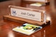 A closeup on a nameplate on a conference table desk. The nameplate reads "Josh Carter - National Security Advisor for Senator Hoeven".