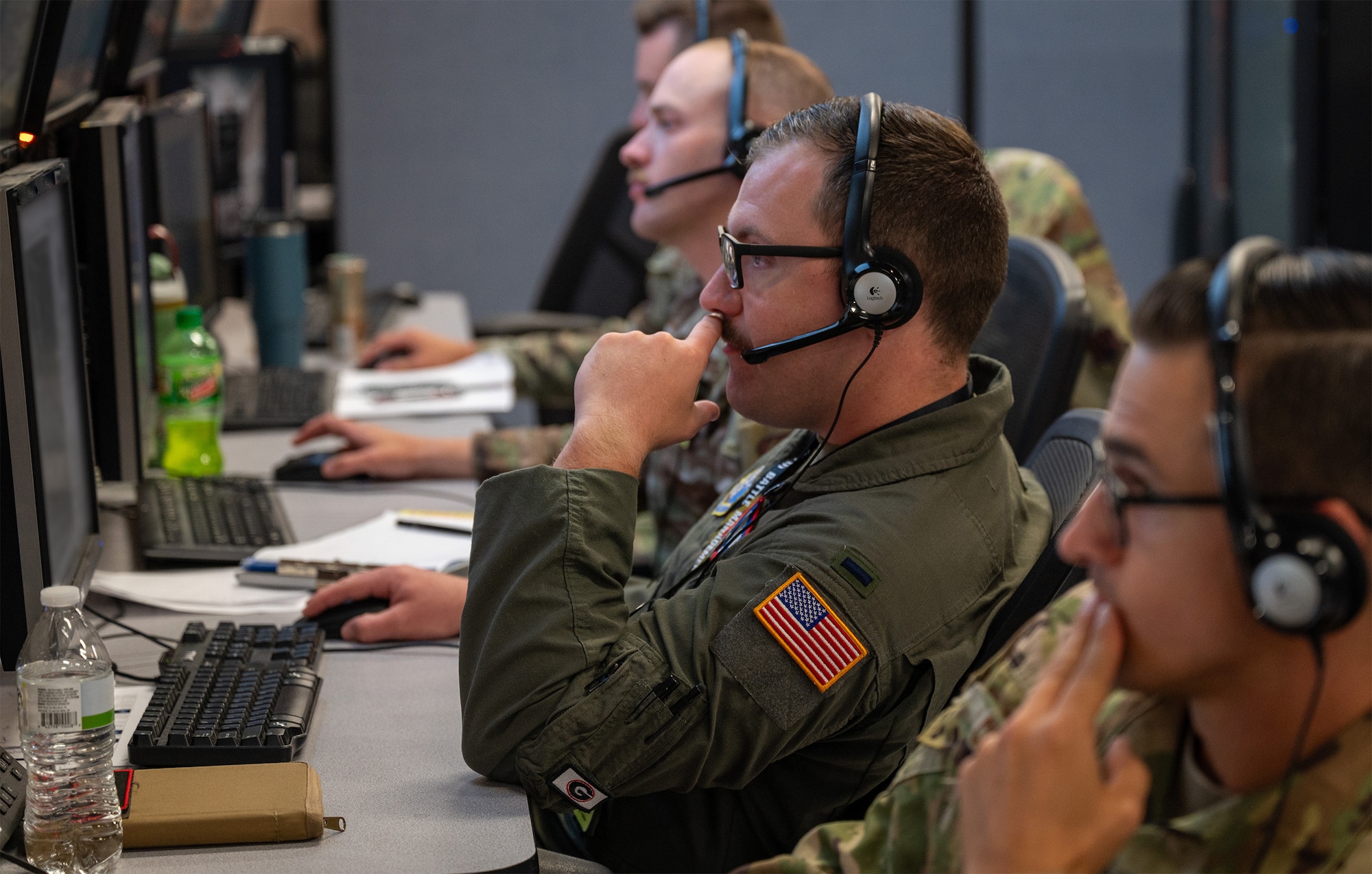 U.S. Air Force Airmen wearing headsets work at computers