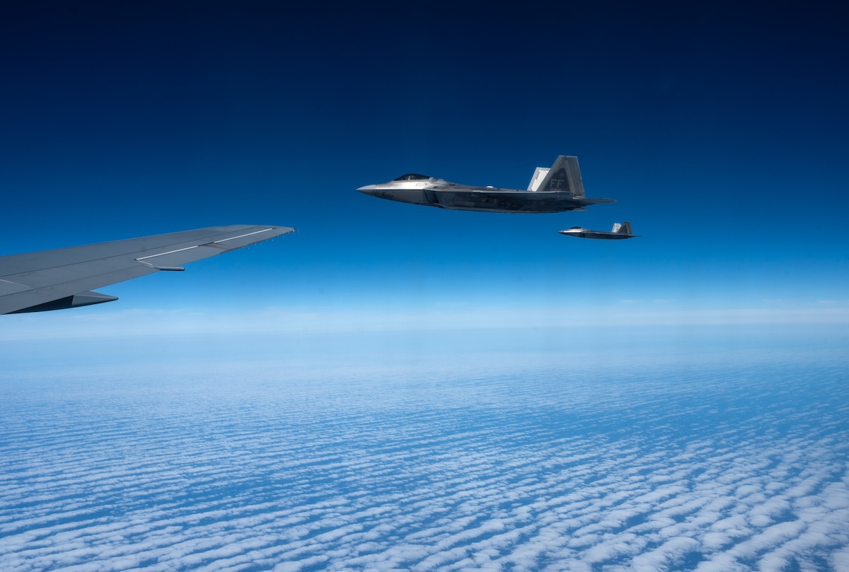 F-22 Raptors assigned to the 1st Fighter Wing, Joint Base Langley-Eustis, Virginia, fly off the wing of a KC-46A Pegasus operated by aircrew assigned to the 22nd Air Refueling Wing, McConnell Air Force Base, Kansas, during Exercise Bamboo Eagle 25-3 Aug. 6, 2025, off the coast of California. Bamboo Eagle 25-3 provides Airmen and joint force participants a flexible, combat-representative, multidimensional battlespace to conduct testing, tactics development, and advanced training in support of U.S. national interests. (U.S. Air Force photo by Staff Sgt. Tryphena Mayhugh)