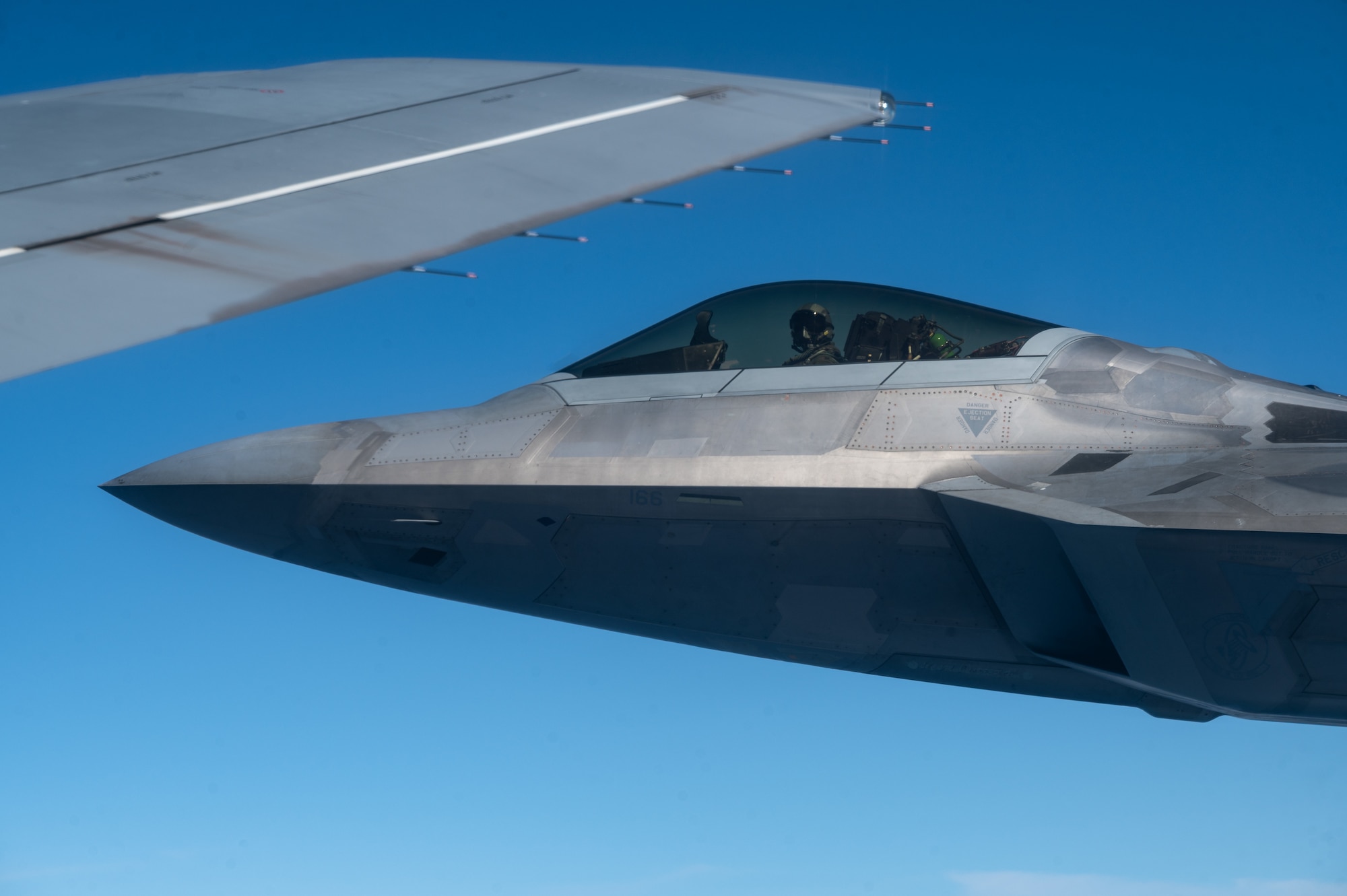 An F-22 Raptor assigned to the 1st Fighter Wing, Joint Base Langley-Eustis, Virginia, flies off the wing of a KC-46A Pegasus operated by aircrew assigned to the 22nd Air Refueling Wing, McConnell Air Force Base, Kansas, during Exercise Bamboo Eagle 25-3 Aug. 6, 2025, off the coast of California. The objective of exercising activities at speed and scale allows the Department of the Air Force to learn from and demonstrate preparedness for complex, large-scale military operations and to improve its ability to operate in a contested, dynamic environment against high-end threats on short notice. (U.S. Air Force photo by Staff Sgt. Tryphena Mayhugh)