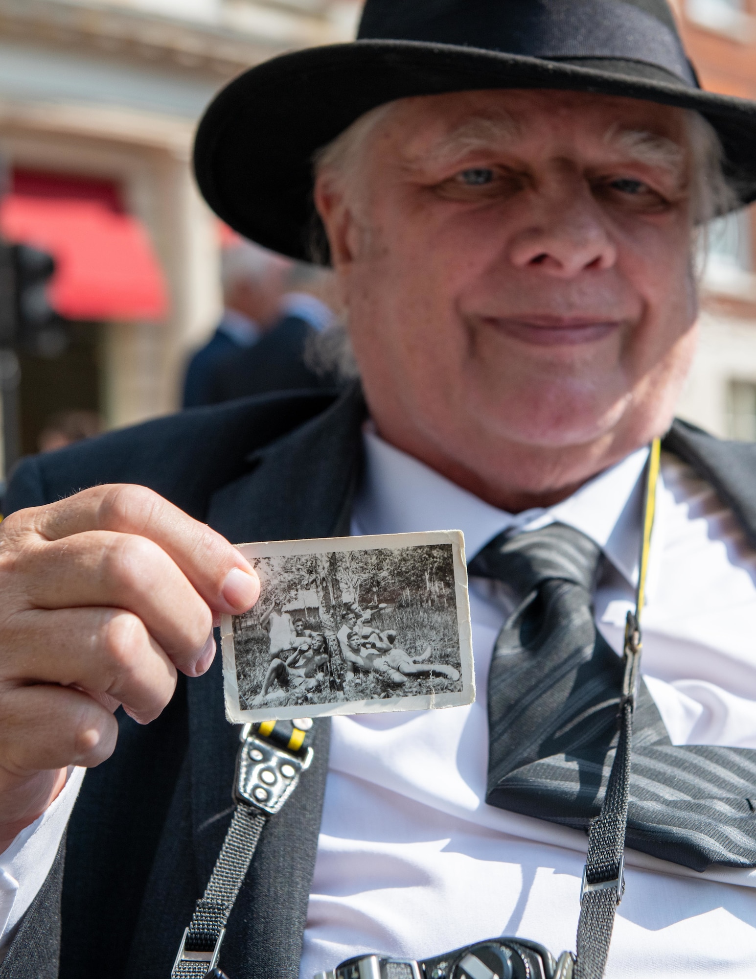 Attendee Gary Merritt holds a photo of his father, Thomas William “Bob” Merritt, and fellow members of the British Royal Artillery during the 80th anniversary Victory over Japan Day ceremony