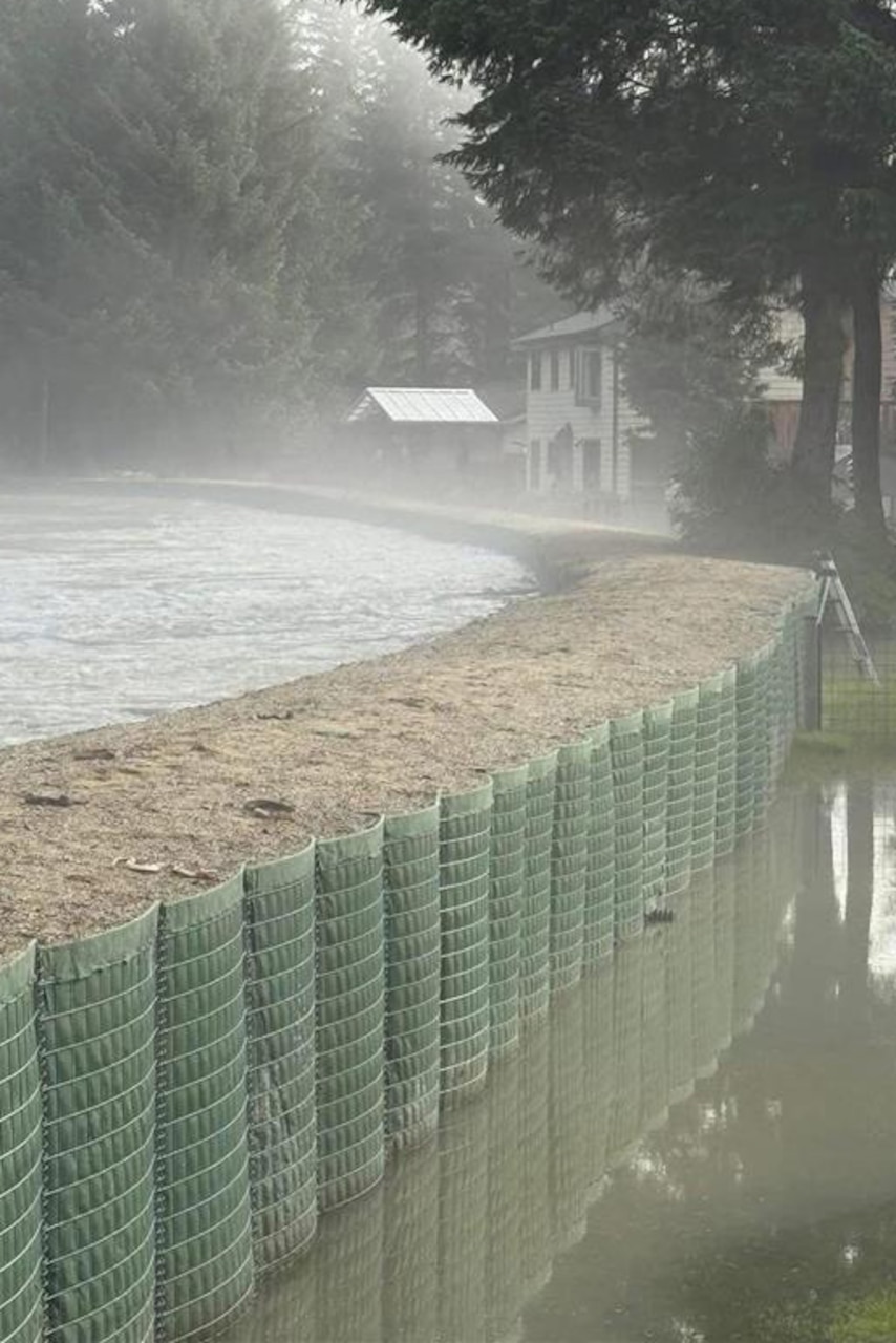 A flood barrier wall holds back water from a swollen river.