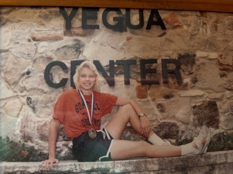 Jennifer Plair, a civil engineering technician at Fort Worth District’s Somerville Lake, sits in front of a sign for the Yegua Center while attending Somerville High School. A decorated long-distance runner, Plair discovered that true leadership lies in fostering teamwork and mentorship.