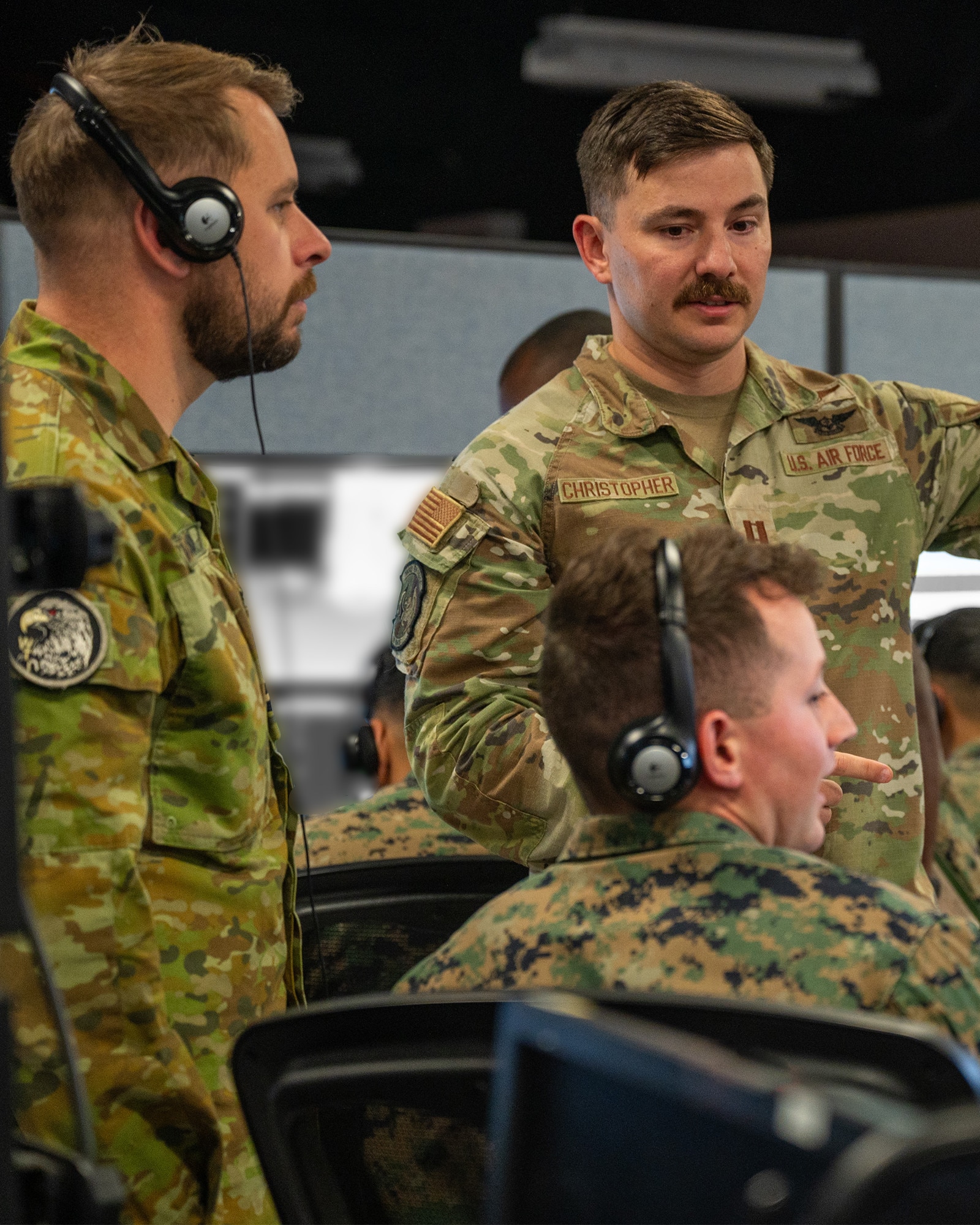 Alt text: uniformed U.S. Marine, U.S. Airman, and Royal Australian Air Force member talking