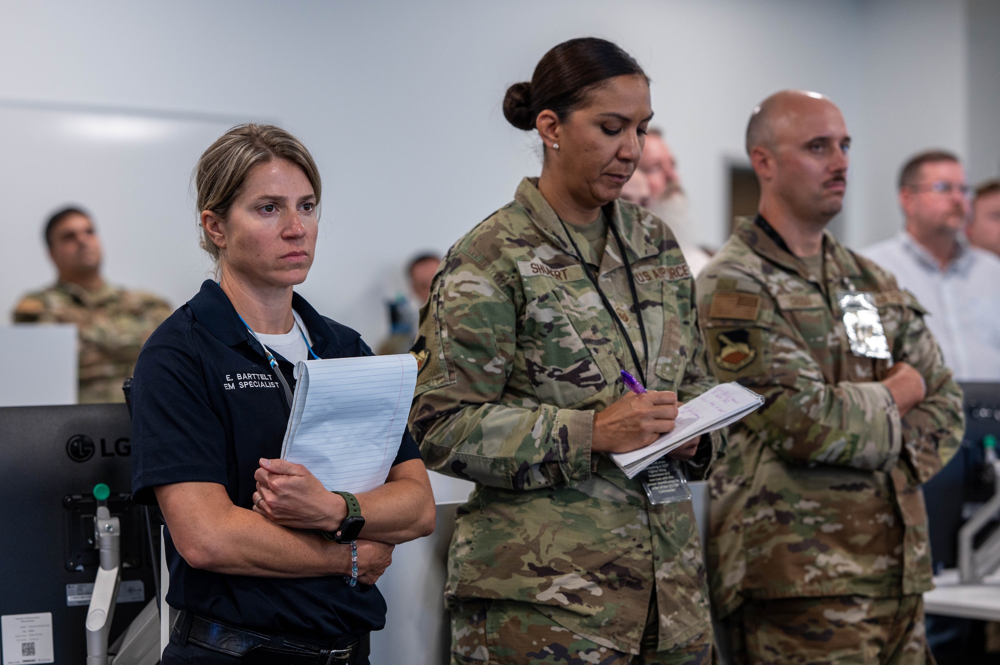 Bay country emergency services member stands with two Air Force members during a hurricane exercise debrief.
