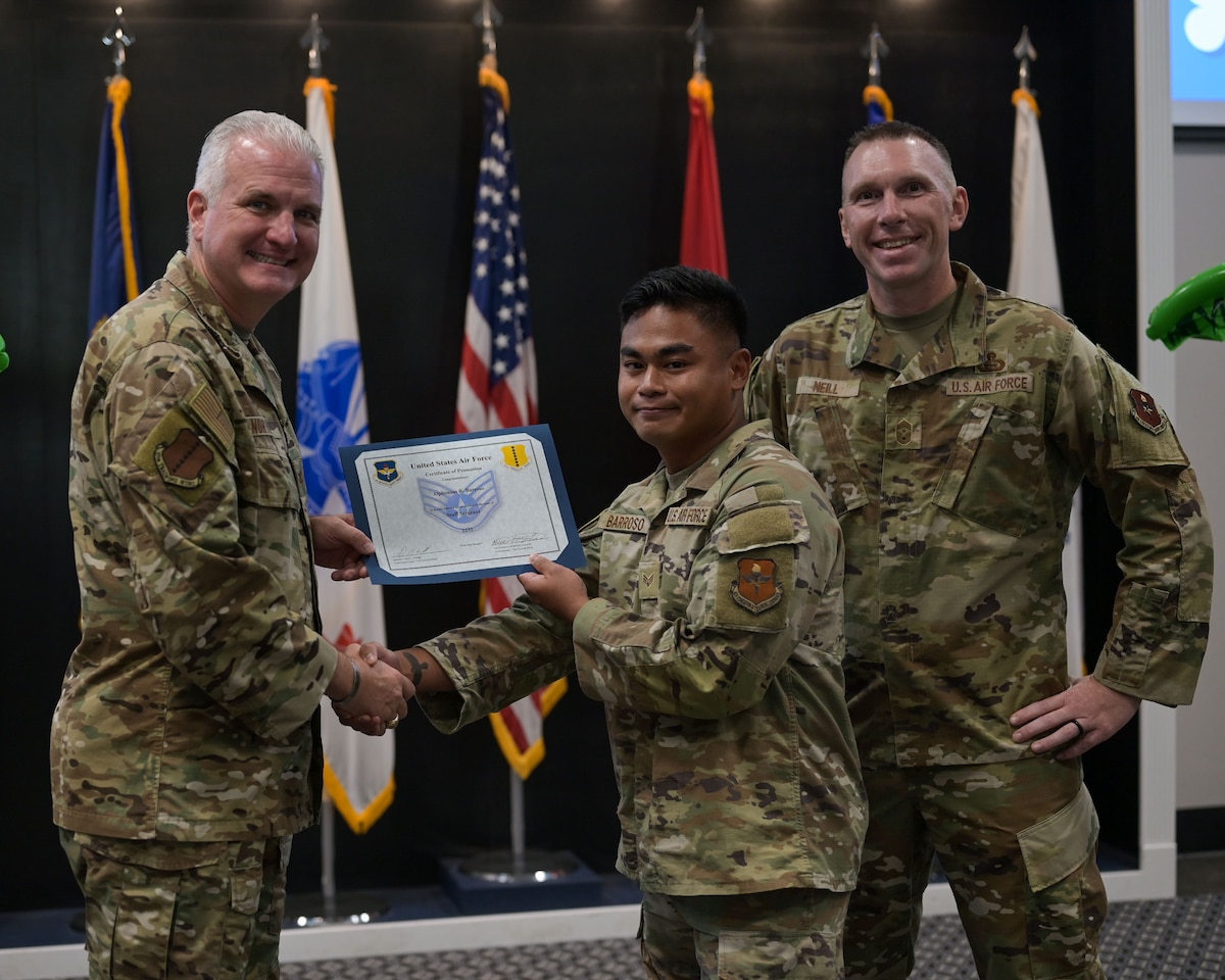 U.S. Air Force Col. Matthew Norton, 17th Training Wing commander and Chief Master Sgt. Derek Neil, 17th TRW command chief, present Senior Airman Alphonsus Barroso, 17 Security Forces Squadron defender, with his Staff Sgt. select certificate at the 25E5 Staff Sgt. release party at the Powell Event Center, Goodfellow Air Force Base, Texas, Aug. 18, 2025. Staff sergeants are the backbone of the Air Force as the first rank of noncommissioned officers and the frontline supervisors who develop their subordinates, develop themselves further, and ensure proper use of resources under their control. (U.S. Air Force photo by Senior Airman Evelyn J. D’Errico)