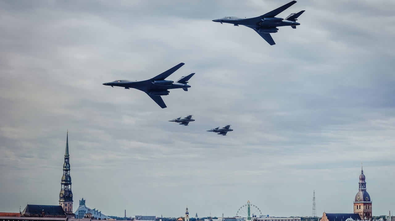 Four fighter jets fly over a European city.