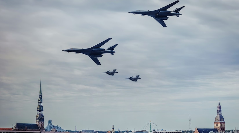 Four fighter jets fly over a European city.