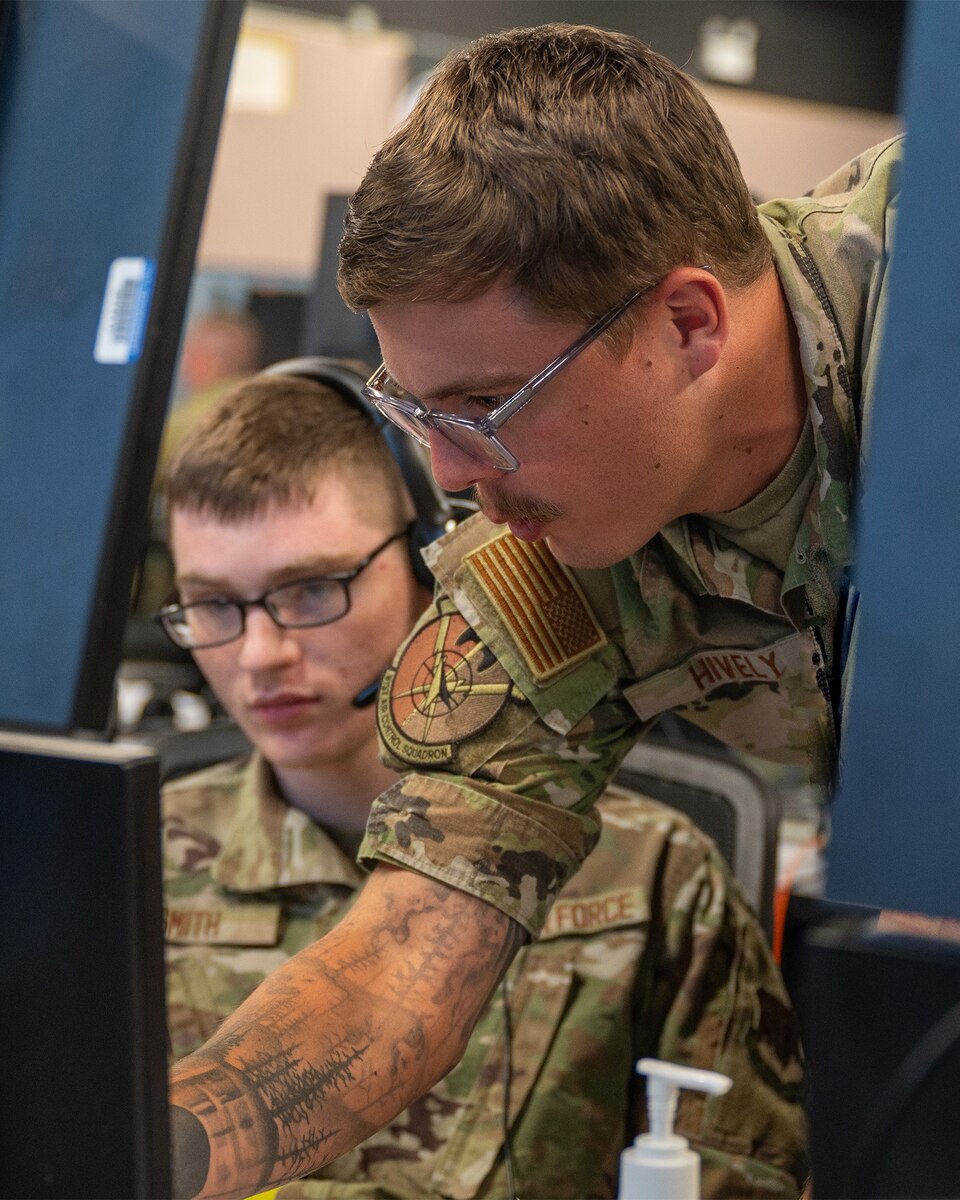 uniformed U.S. Airmen work at computers