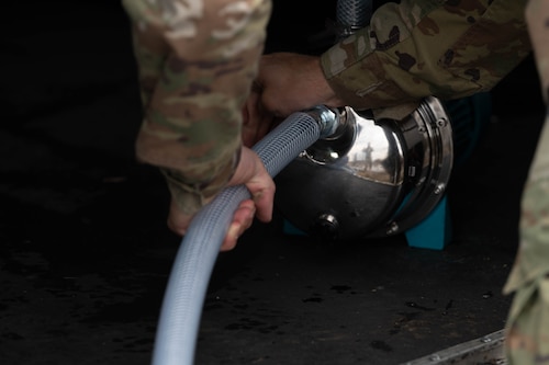 A person fixing a hose to a canister