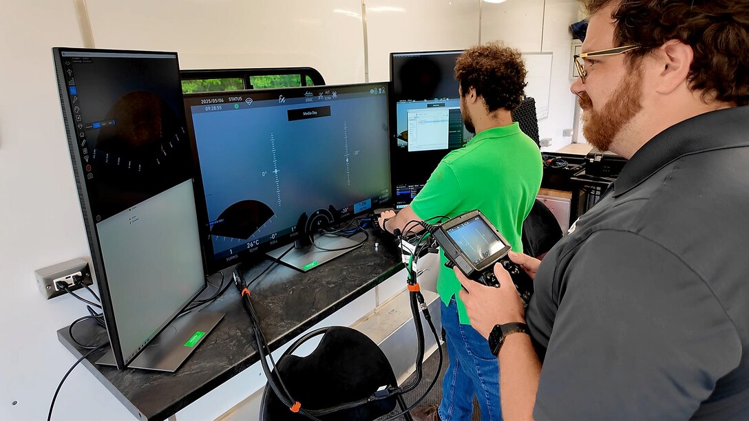 Andrew Steen (far right) and Brandon McGrew control the underwater remotely operated vehicle (ROV) from a custom command trailer.