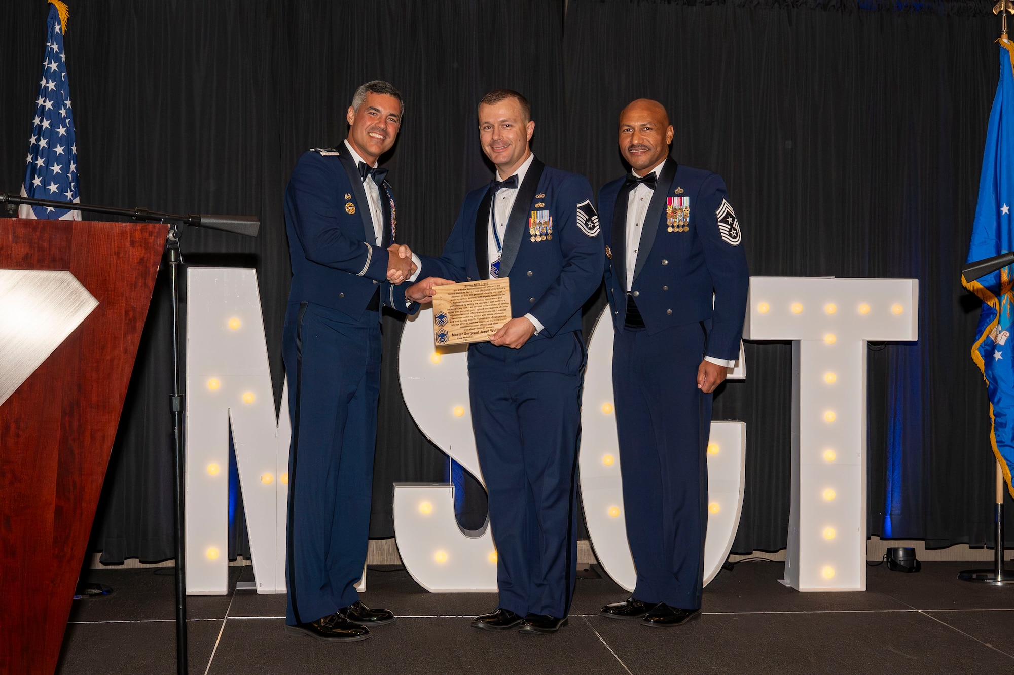 U.S. Air Force Col. Jose Cabrera, 355th Wing commander, left, Chief Master Sgt. Kelvin Hatcher, 355th Wing command chief, right, and Master Sgt. Jered Weisnicht, 355th Comptroller squadron flight chief, pose for a photo during the SNCO induction ceremony in Tucson, Arizona, Aug. 15, 2025. The ceremony recognized the accomplishments of Airmen promoted to the rank of master sergeant and celebrated their transition into the senior enlisted tier. (U.S. Air Force photo by Airman 1st Class Samantha Melecio)