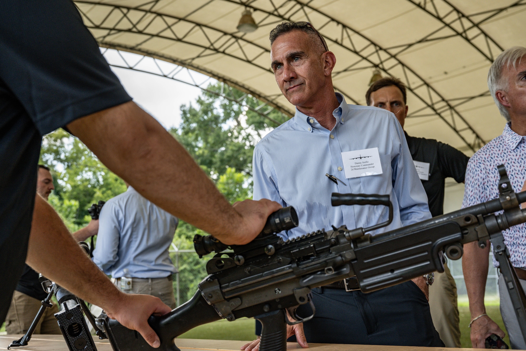 Danny Aiello, Aviation Tech Group manager and 2nd Maintenance Group honorary commander, listens to a Combat Arms Training and Maintenance Airman talk about their weaponry