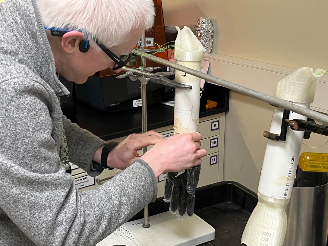 To extend the life of their 3D hand model used in glove testing, PTC engineer Edward Dalton applies a layer of rubber and plastic gloves. This acts as a barrier, preventing wear and tear from the fuel.