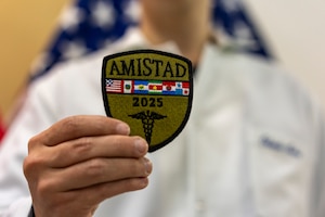 A Paraguayan volunteer displays the AMISTAD 2025 mission patch during a closing ceremony recognizing local student contributions at Hospital General de Luque, in Paraguay, Aug. 14, 2025. Volunteers worked side-by-side with the United States and Paraguayan medical teams throughout the two-week global health engagement mission. (U.S. Air Force photo by Andrea Jenkins)