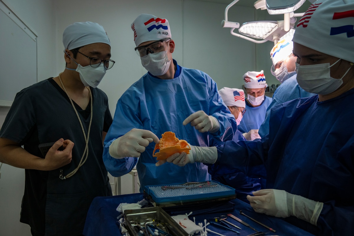 U.S. Air Force Maj. Brad Pfeifle, 943rd Aerospace Medicine Squadron dentist, explains surgical techniques to Jiin Choi, Paraguayan dental student, during a maxillofacial surgery procedure at Hospital General de Luque, in Paraguay, Aug. 9, 2025. U.S. Air Force and Paraguayan medical teams worked side by side as part of AMISTAD 2025, a global health engagement mission designed to strengthen partnerships, increase medical readiness and expand access to care. (U.S. Air Force photo by Andrea Jenkins)