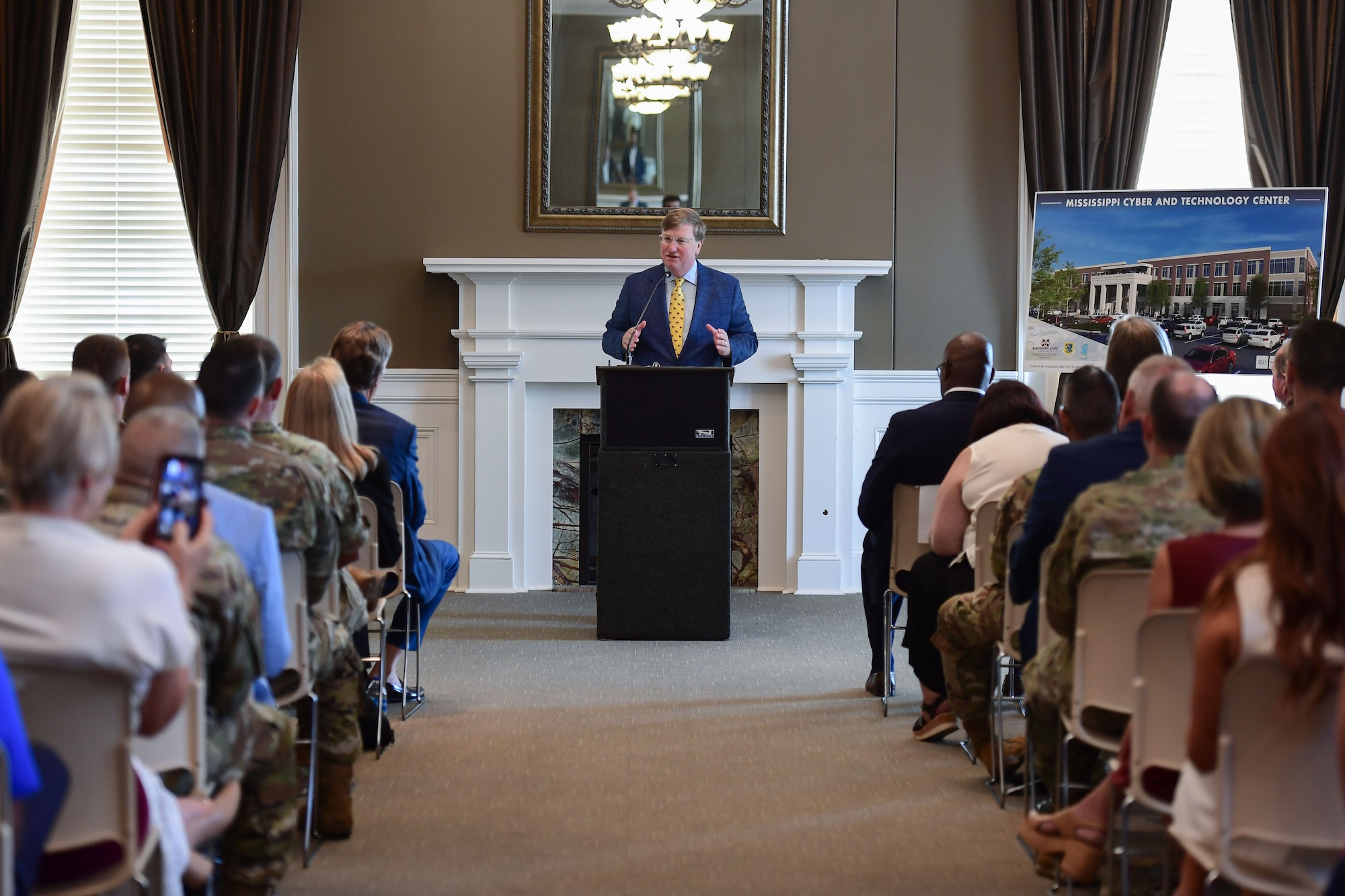 A man stands behind a podium while speaking to an audience.
