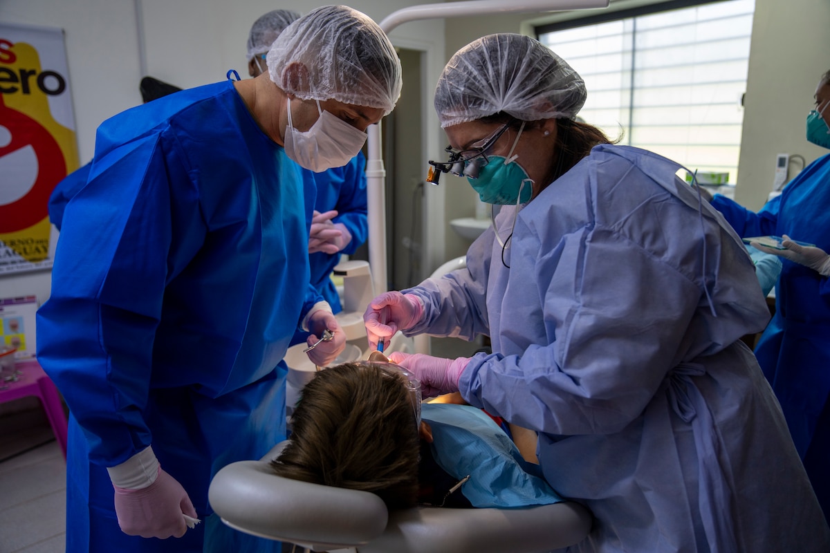 U.S. Air Force Lt. Col. Alexandra Hernandez, 507th Medical Squadron dentist, right, and a dental technician, perform an extraction on a patient at the Unidad de Salud de la Familia Tarumandy in Luque, Paraguay, Aug. 13, 2025. The U.S. Southern Command and U.S. Embassy in Asuncion donated a fully equipped dental suite and 17,000 pairs of prescription eyeglasses to the Ministry of Health, expanding care for local residents. (U.S. Air Force photo by Andrea Jenkins)