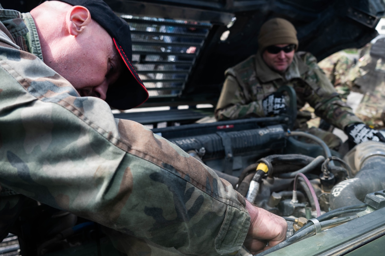 Maryland Air National Guard Staff Sgt. Jonathan Bandy, a vehicle mechanic with the 175th Logistics Readiness Squadron, observes a civilian member of the Armed Forces of Bosnia and Herzegovina conduct engine maintenance during a convoy from Zenica to Visoko, in Kakanj, Bosnia and Herzegovina, April 7, 2025.