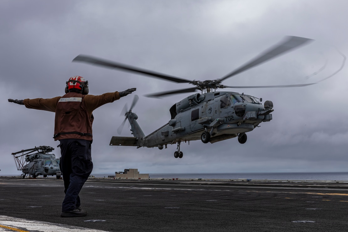 Aviation Electronics Technician Airman Apprentice David Benito, from Los Angeles, signals an MH-60R Sea Hawk helicopter, attached to Helicopter Maritime Strike Squadron (HSM) 71, as it takes off from the flight deck of the Nimitz-class aircraft carrier USS Abraham Lincoln (CVN 72).