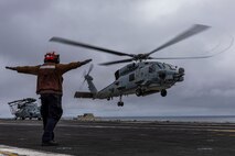 Aviation Electronics Technician Airman Apprentice David Benito, from Los Angeles, signals an MH-60R Sea Hawk helicopter, attached to Helicopter Maritime Strike Squadron (HSM) 71, as it takes off from the flight deck of the Nimitz-class aircraft carrier USS Abraham Lincoln (CVN 72).