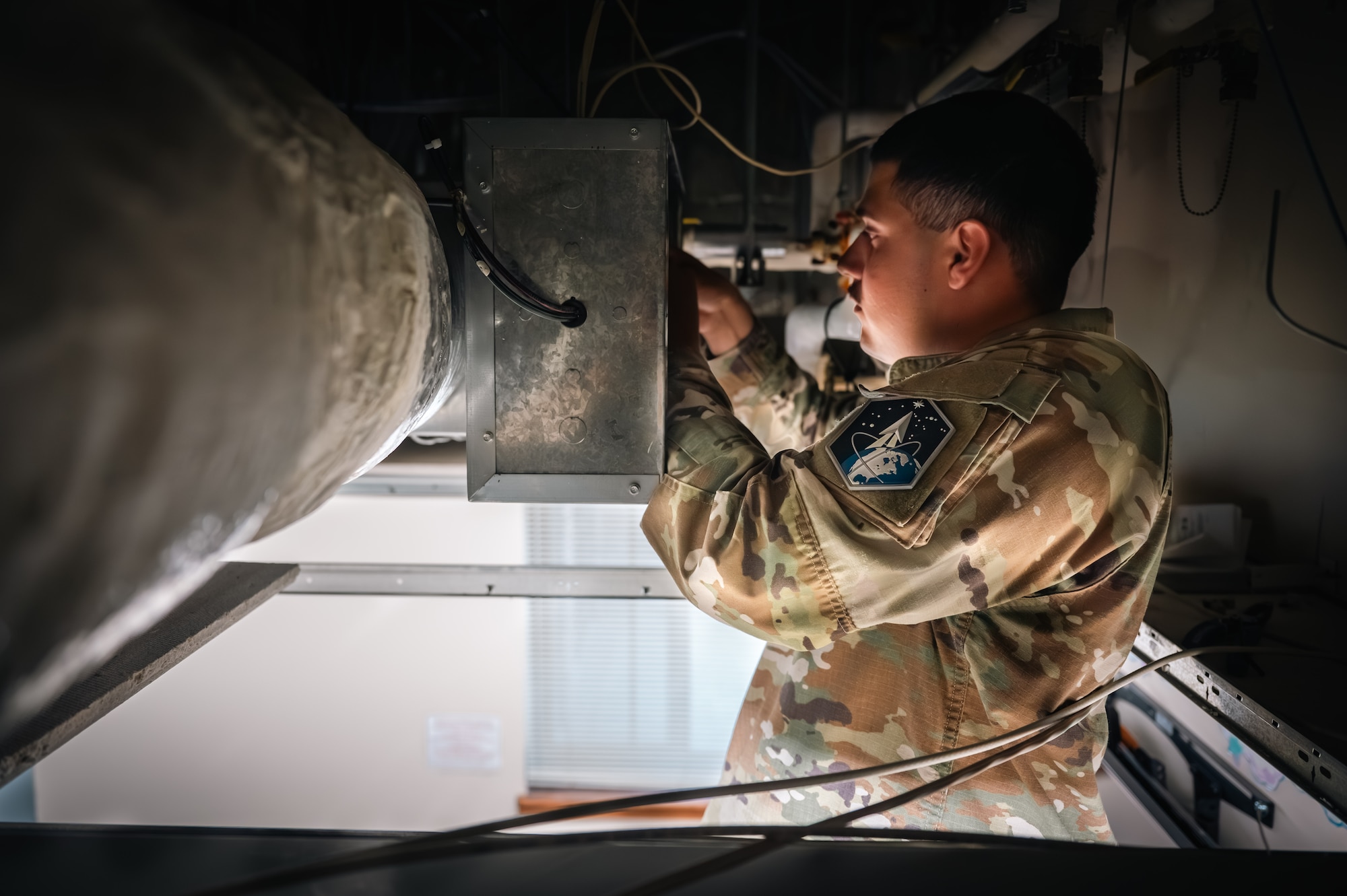 man works on hvac system in military uniform