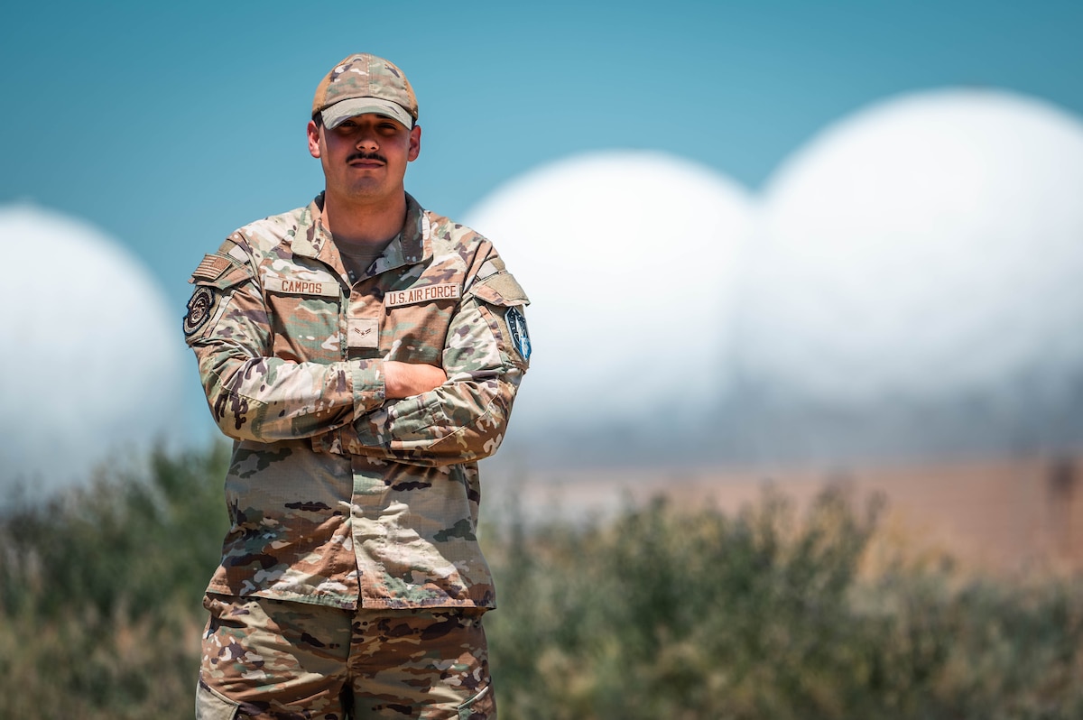 man stands with arms folded in military uniform