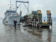 A U.S. Army Landing Craft Utility (LCU) conducts the first-ever roll-on/roll-off operation at JTDC Subic Shared North Dock in the Philippines, loading an armored personnel carrier during SABAK 25, marking a milestone in joint maritime logistics and operational capability.