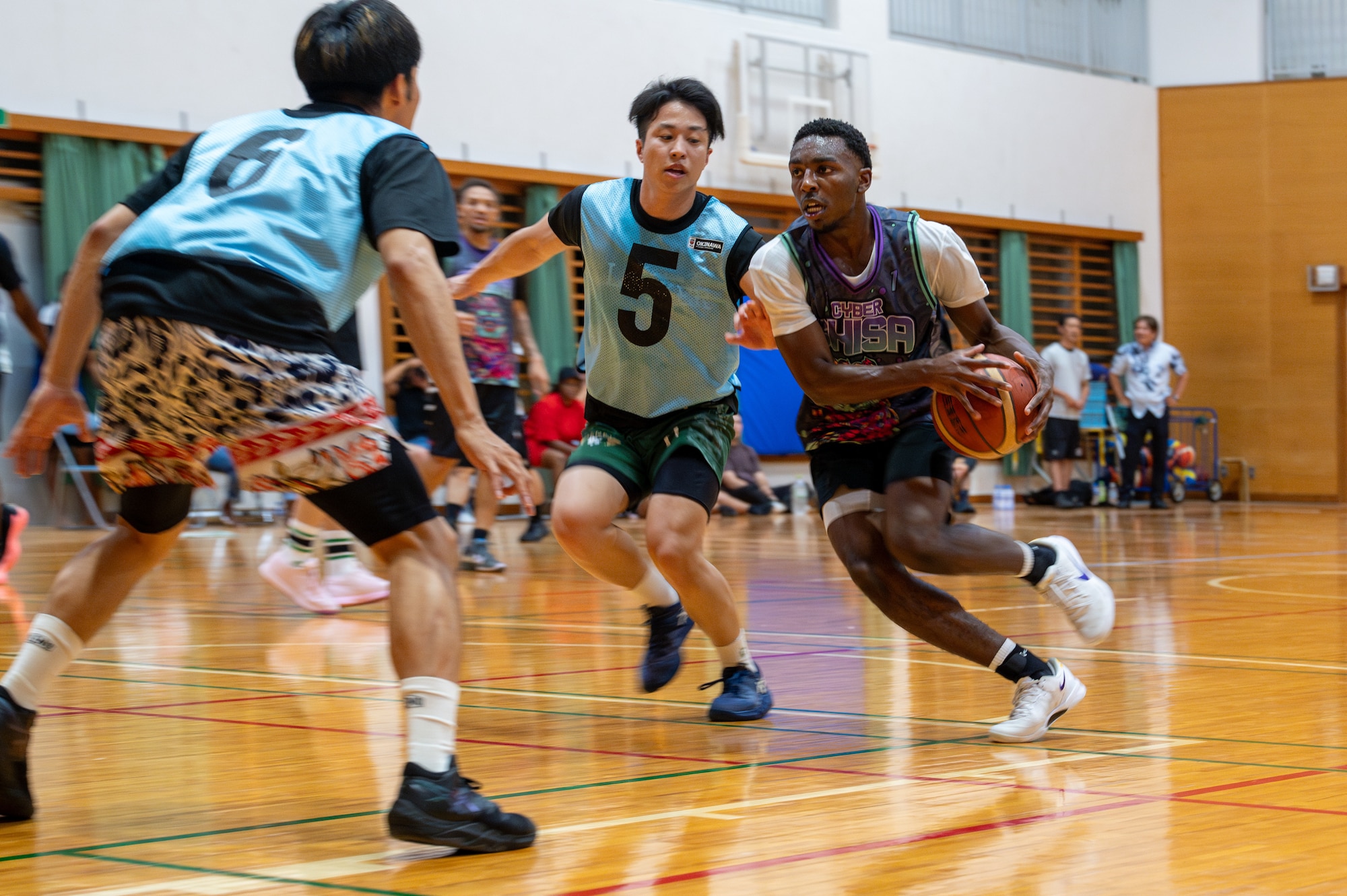 An Airman with 18 CS breaks through the defensive line of the opposite team during a basketball match