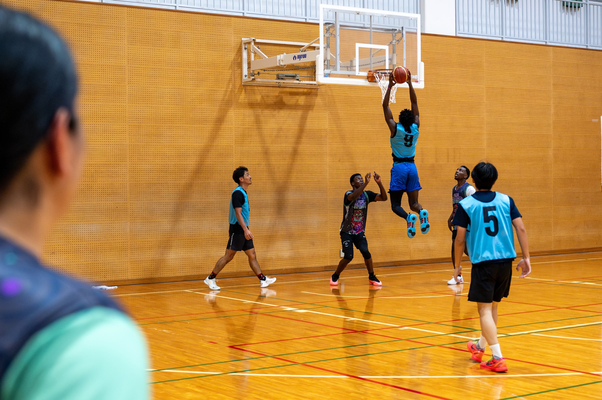 A basketball player slam dunks on the court