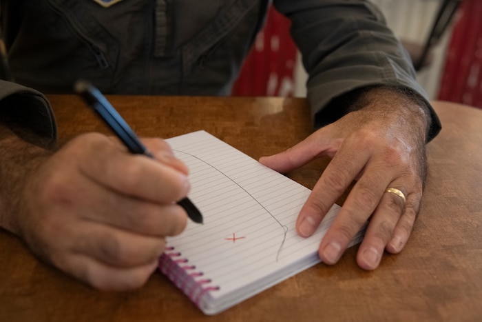 Maj. Alex Boykin sketches out the cone of Hurricane Sally and the coast on a spiral notebook.
