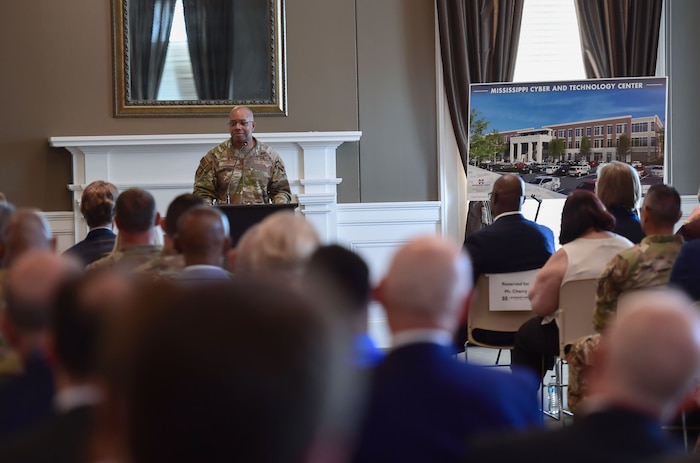 A man in military uniform speaks to an audience from behind a podium.