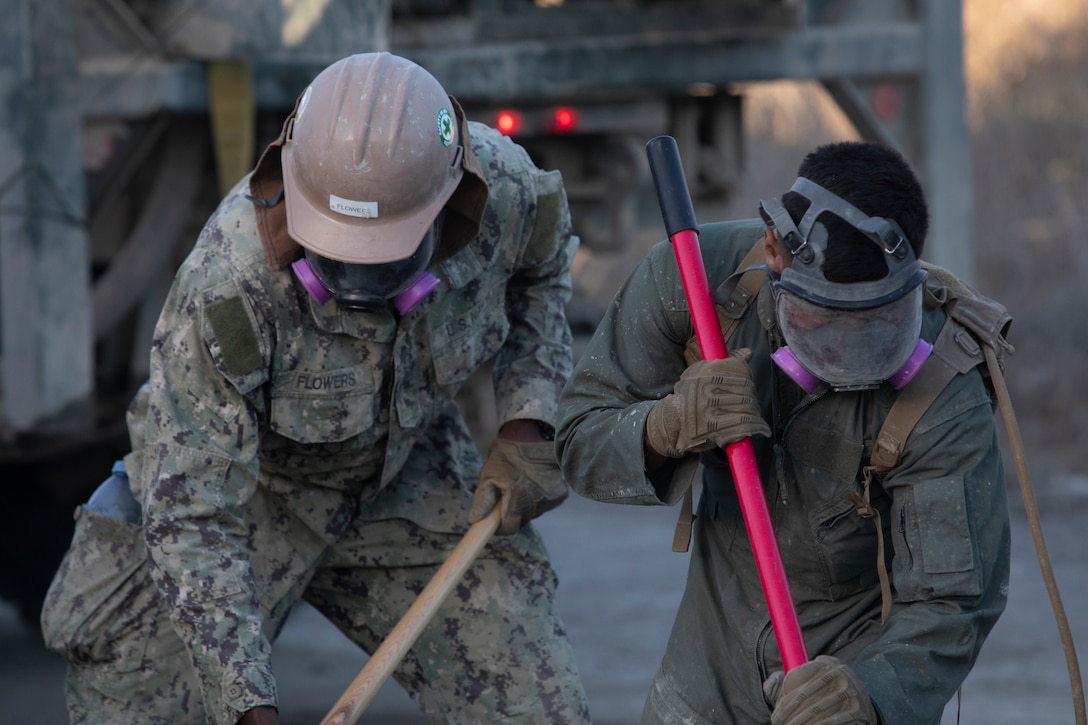 U.S. Navy Seaman Tristian Flowers, left, a builder constructionman with Airfield Construction Company Bravo, Naval Mobile Construction Group 5, Naval Construction Force, and U.S. Marine Corps Lance Cpl. Jose Rodriguez, a combat engineer with Marine Wing Support Squadron 372, Marine Air Control Group 38, 3rd Marine Aircraft Wing, rake concrete during Operation Resilient Spear at Vandenberg Space Force Base, California, Aug. 8, 2025. Operation Resilient Spear is an opportunity for Marines with MWSS-372 to integrate and train with NMCB-5 through Base Recovery After Attack and Airfield Damage Repair Training to increase interoperability between Marine Corps engineers and Navy Seabees. Flowers is a native of New York, and Rodriguez is a native of California. (U.S. Marine Corps photo by Lance Cpl. Alexander Vaughn)