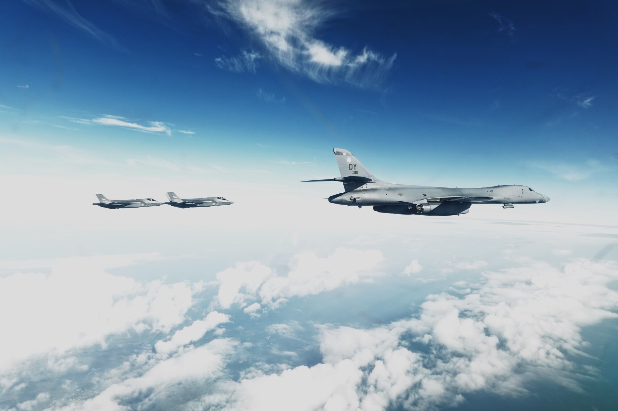B-1 flies in the sky next to two F-35s