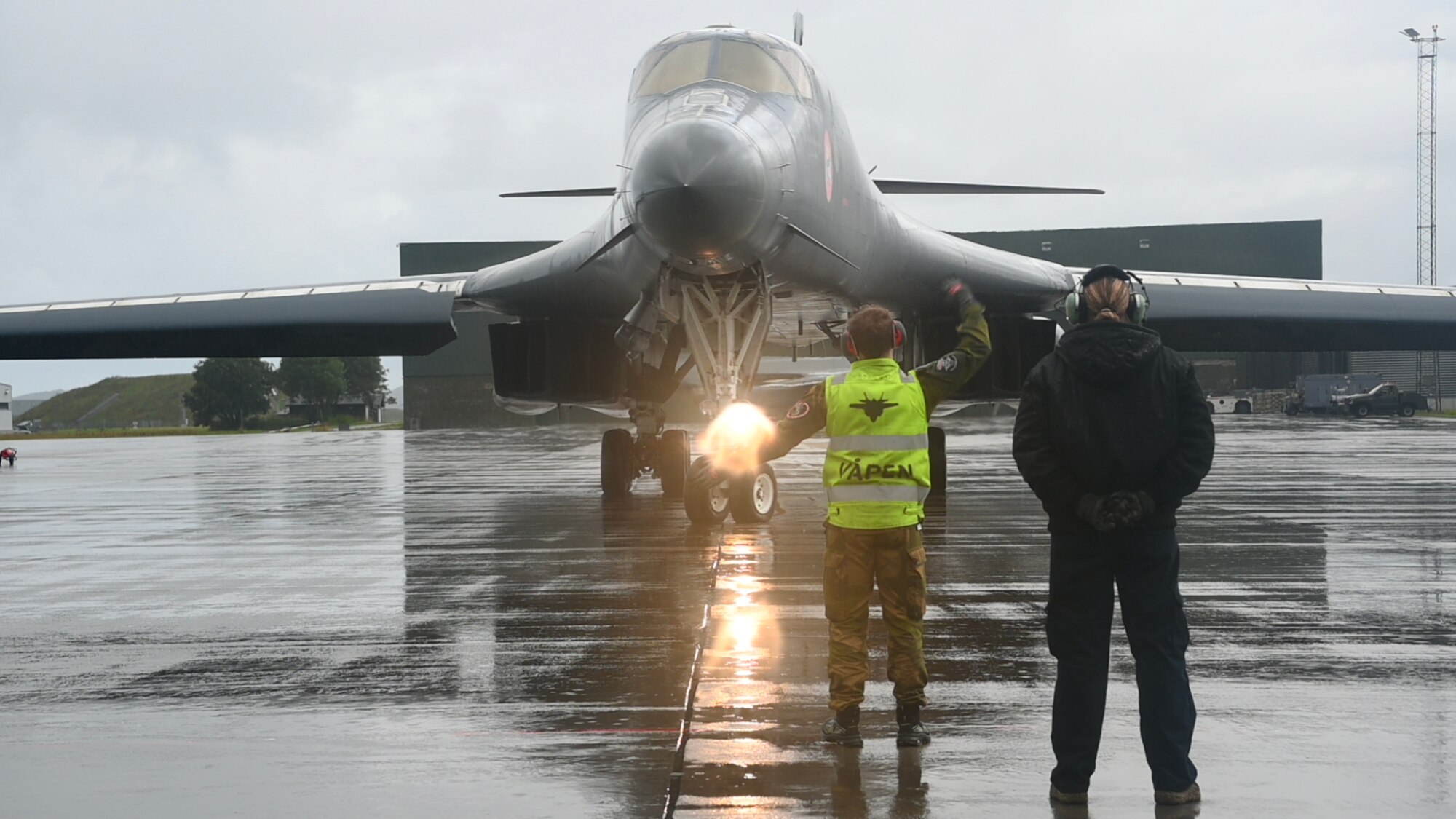 airmen marshal a B-1 to taxi in the rain