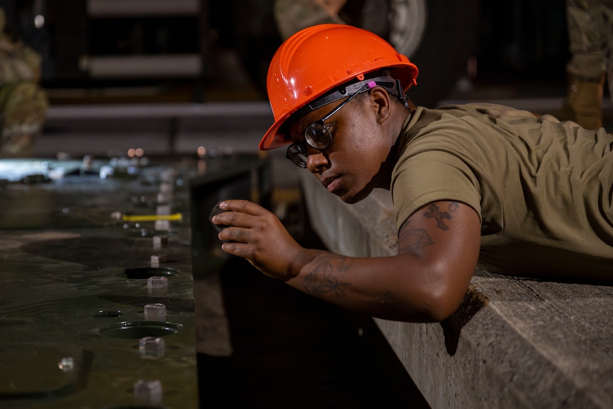 A U.S. Air Force Airman assigned to the 35th Civil Engineer Squadron examines a component during the installation of a new aircraft arresting system at Misawa Air Base, Japan, Aug. 19, 2025.