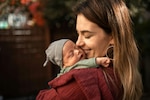 Smiling woman holds a baby.