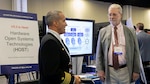 Capt. Jarrod Hair, left, Air Combat Electronics Program Office program manager, speaks with Karlson Greene about the importance of a modular open systems approach (MOSA) and collaboration during the MOSA Summit 2024.