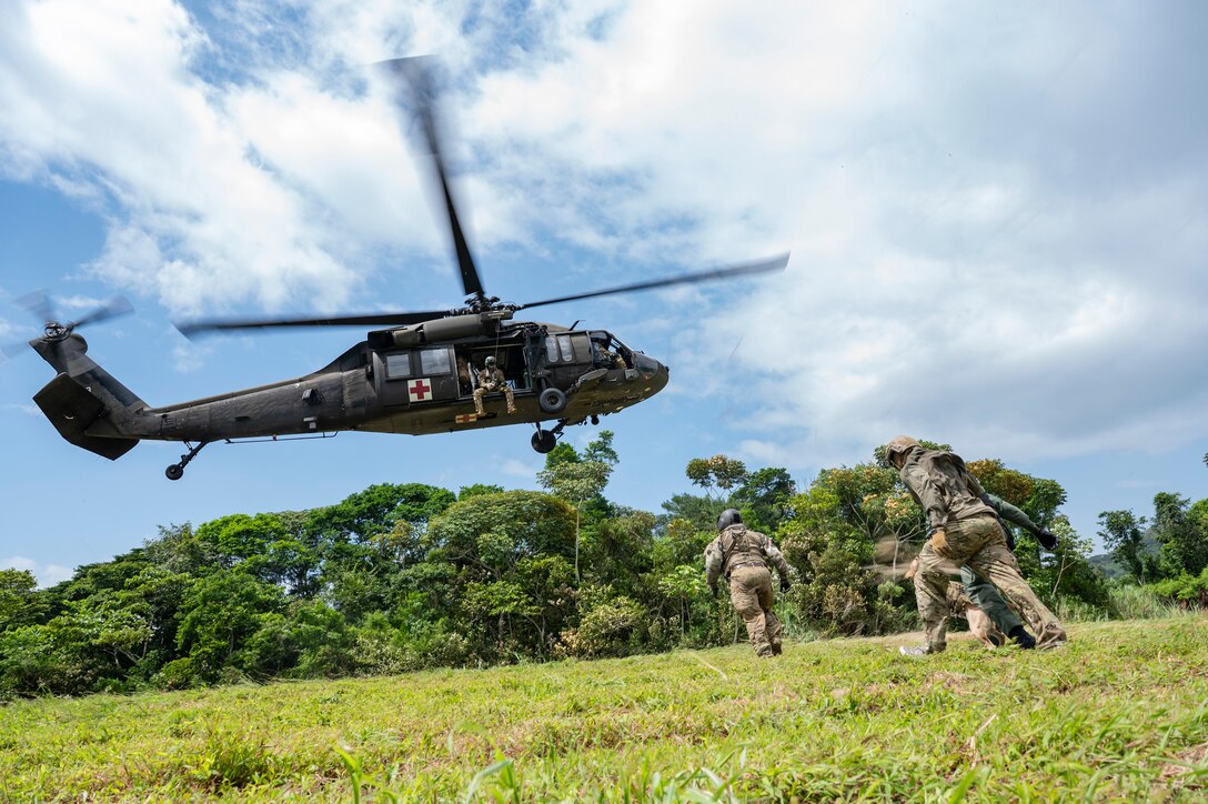 An HH-60 Blackhawk assigned to 1st Battalion, 228th Aviation Regiment, out of Soto Cano Air Base, Honduras, hovers as Panamanian soldiers make an approach during PANAMAX-Alpha Phase I, at Cerro Tigre, Panama, July 15, 2025. PANAMAX is a joint exercise designed to enhance interoperability among participating nations and strengthen their ability to conduct multinational operations, particularly to defend the Panama Canal. (U.S. Air Force photo by Staff Sgt. Sadie Colbert)