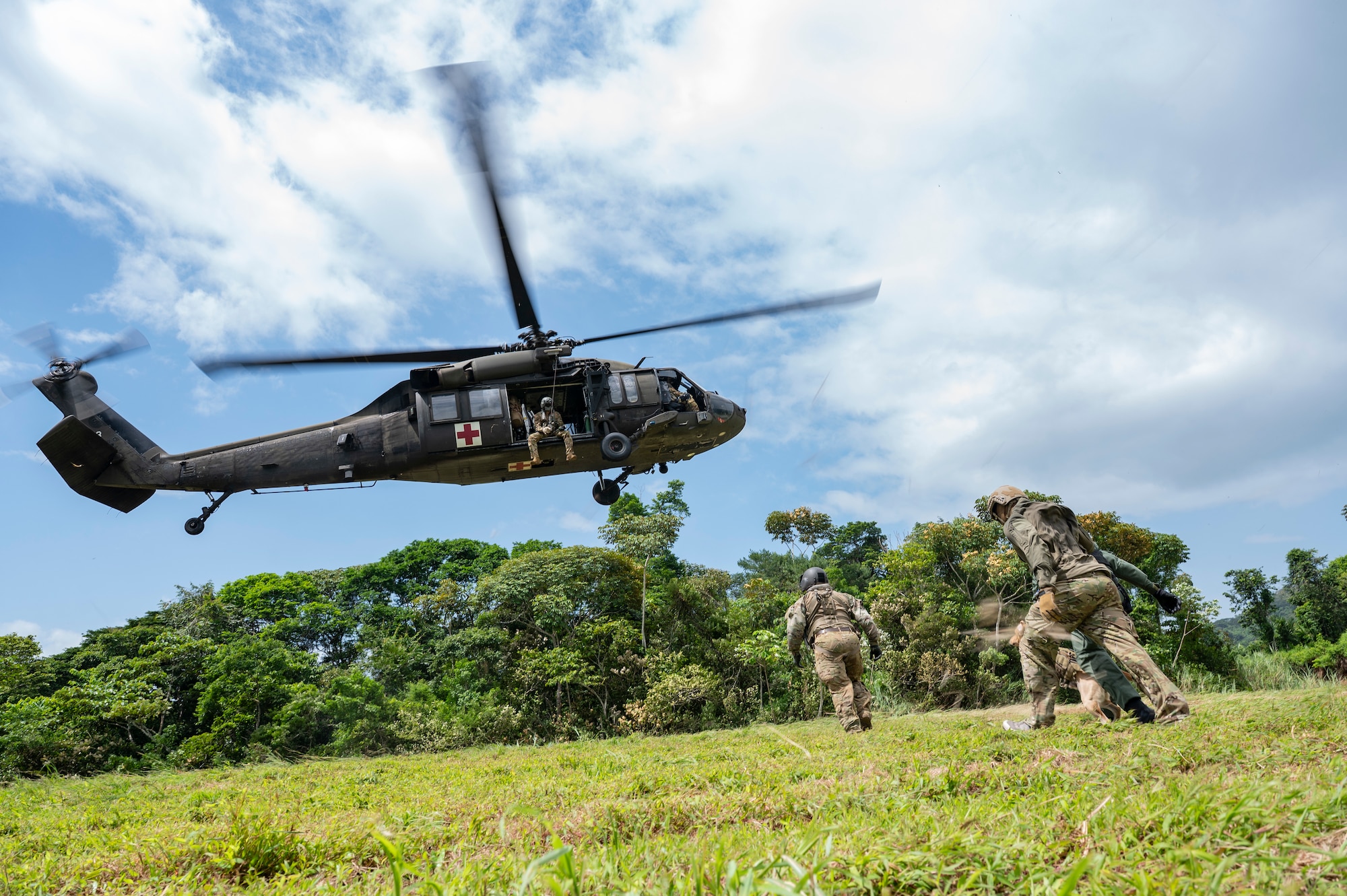 An HH-60 Blackhawk assigned to 1st Battalion, 228th Aviation Regiment, out of Soto Cano Air Base, Honduras, hovers as Panamanian soldiers make an approach during PANAMAX-Alpha Phase I, at Cerro Tigre, Panama, July 15, 2025. PANAMAX is a joint exercise designed to enhance interoperability among participating nations and strengthen their ability to conduct multinational operations, particularly to defend the Panama Canal. (U.S. Air Force photo by Staff Sgt. Sadie Colbert)
