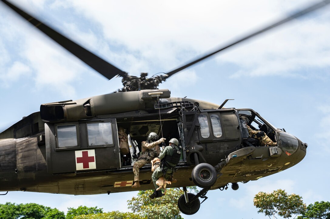 An HH-60 Blackhawk assigned to 1st Battalion, 228th Aviation Regiment, out of Soto Cano Air Base, Honduras, hoist a Panamanian soldier and his bomb-detection K-9 during PANAMAX-Alpha Phase I, at Cerro Tigre, Panama, July 15, 2025. PANAMAX-Alpha Phase I is a government of Panama exercise supported by U.S. Southern Command, focused on security of the canal in Panama. The portion JTF-Bravo is participating in for phase one includes providing hot and cold load training, K-9 familiarization and hoist training, medical evacuation, fast rope insertion and aerial overwatch training with our helicopters and partners. (U.S. Air Force photo by Staff Sgt. Sadie Colbert)