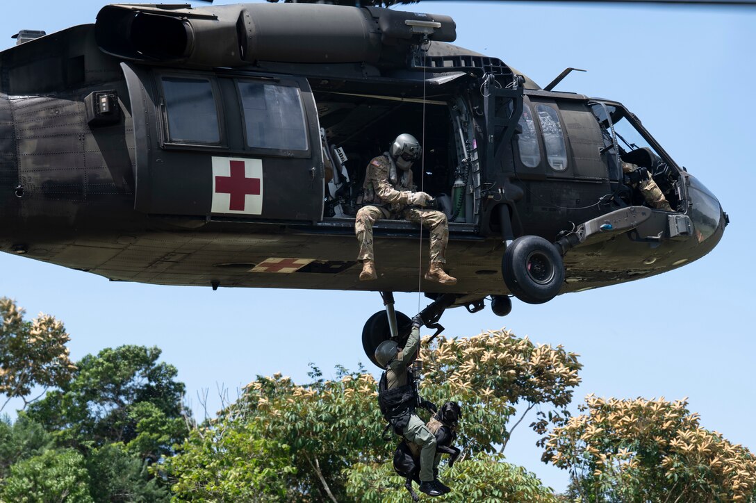 An HH-60 Blackhawk assigned to 1st Battalion, 228th Aviation Regiment, out of Soto Cano Air Base, Honduras, hoist a Panamanian soldier and his bomb-detection K-9 during PANAMAX-Alpha Phase I, at Cerro Tigre, Panama, July 15, 2025. PANAMAX-Alpha Phase I is a government of Panama exercise supported by U.S. Southern Command, focused on security of the canal in Panama. The portion JTF-Bravo is participating in for phase one includes providing hot and cold load training, K-9 familiarization and hoist training, medical evacuation, fast rope insertion and aerial overwatch training with our helicopters and partners. (U.S. Air Force photo by Staff Sgt. Sadie Colbert)