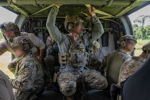 Several U.S. Naval Special Warfare operators prepare to descend from a UH-60 Blackhawk assigned to 1st Battalion, 228th Aviation Regiment, out of Soto Cano Air Base, Honduras, during PANAMAX-Alpha Phase I, at Cerro Tigre, Panama, July 15, 2025. PANAMAX is an annual joint exercise designed to enhance interoperability among participating nations and strengthen their ability to conduct multinational operations, particularly to defend the Panama Canal. (U.S. Air Force photo by Staff Sgt. Sadie Colbert)