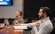 Charles Costanzo sits at a conference table, receiving a briefing during a staff delegation.